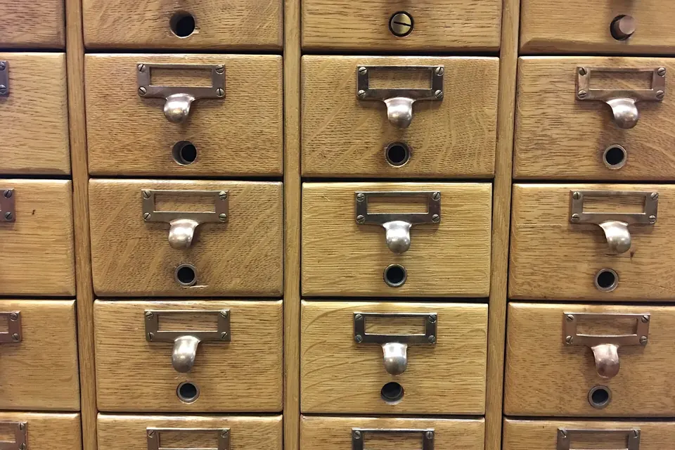 Rows of small wooden card catalogue drawers with metal pulls