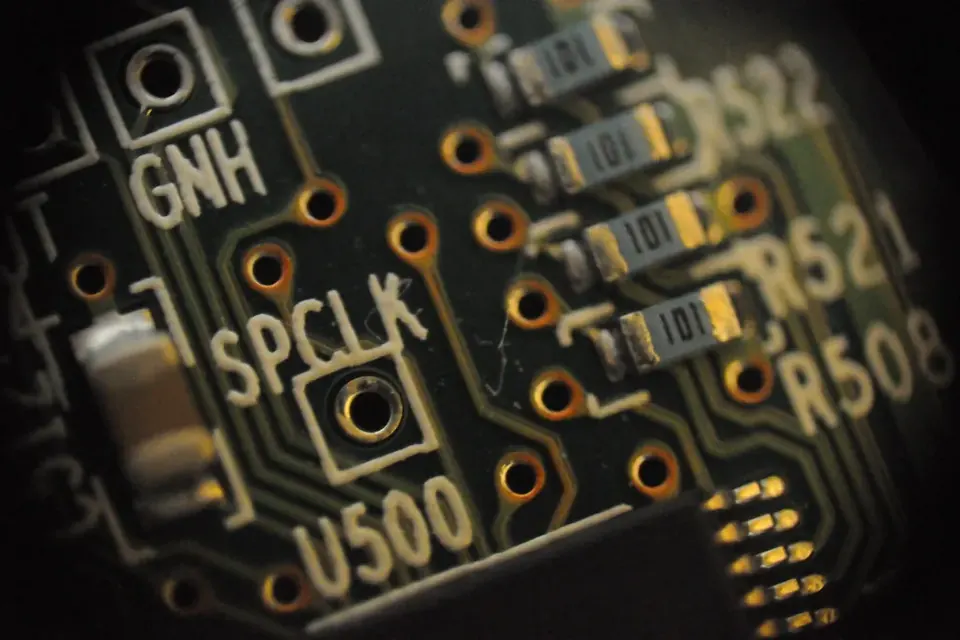 Macro photograph of a dark printed circuit board with silkscreen labels, pads and small surface-mount components