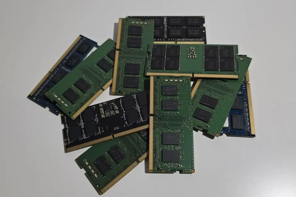 Several laptop memory modules with black chips and gold contacts lying on a light surface